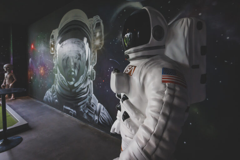 Drive Shack's Mini Golf Course, themed by Puttery, lights up with neon space art, creating an out-of-this-world nighttime play experience.